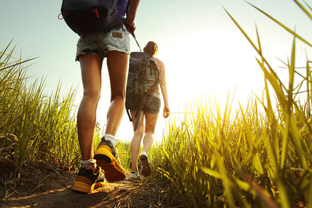 Two individuals walking along a trail surrounded by tall grass, enjoying a serene outdoor experience.