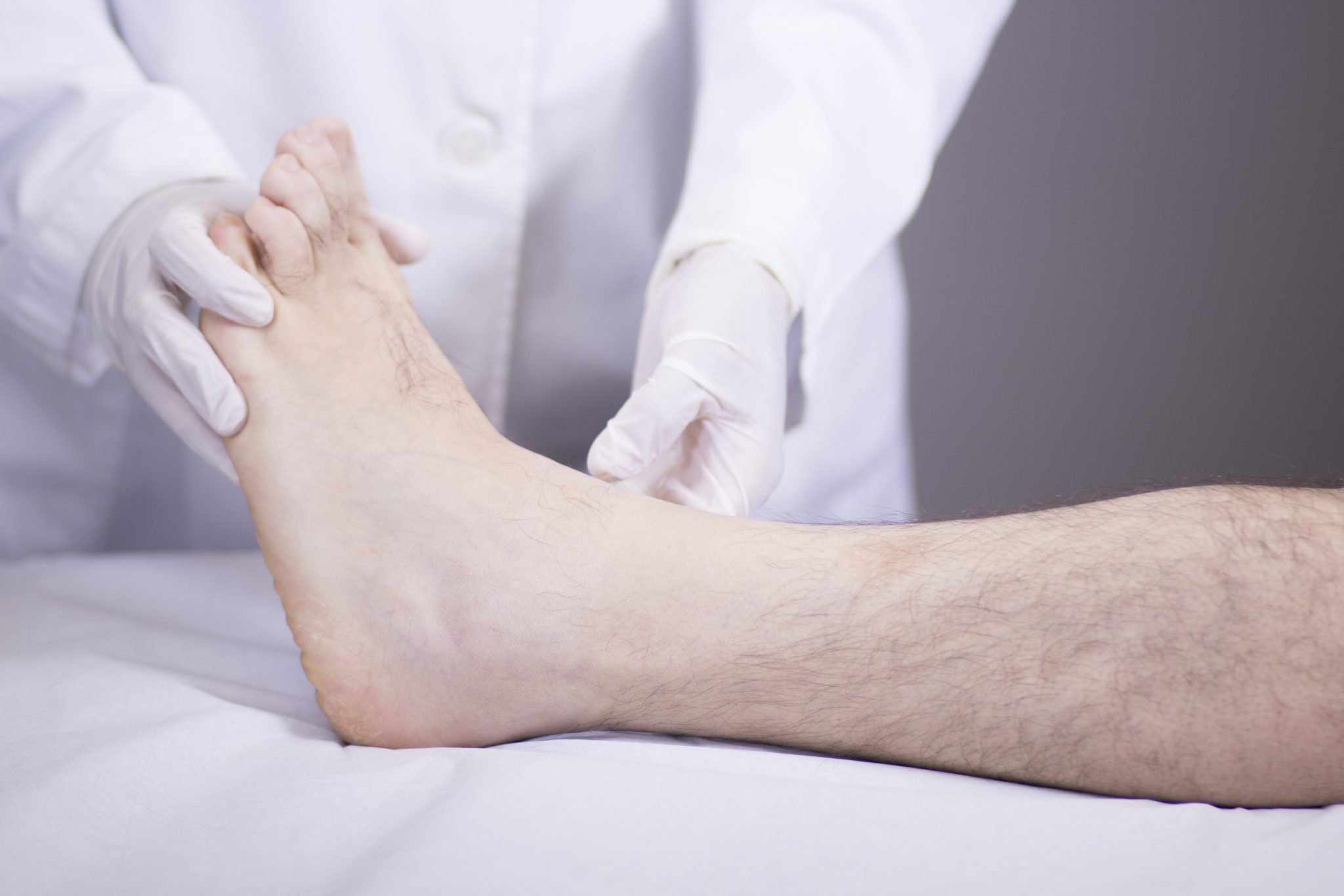 A doctor examines a patient's foot during a medical check-up in a clinical setting.