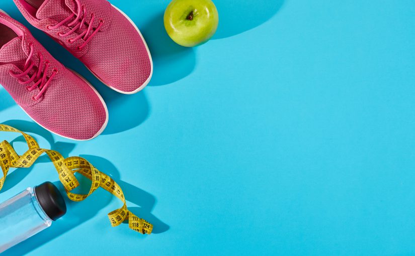 A pair of pink sneakers, a water bottle, and a measuring tape arranged on a blue background.