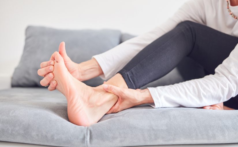 A woman sits comfortably on a couch, resting her foot on the couch while relaxing in a cozy setting.