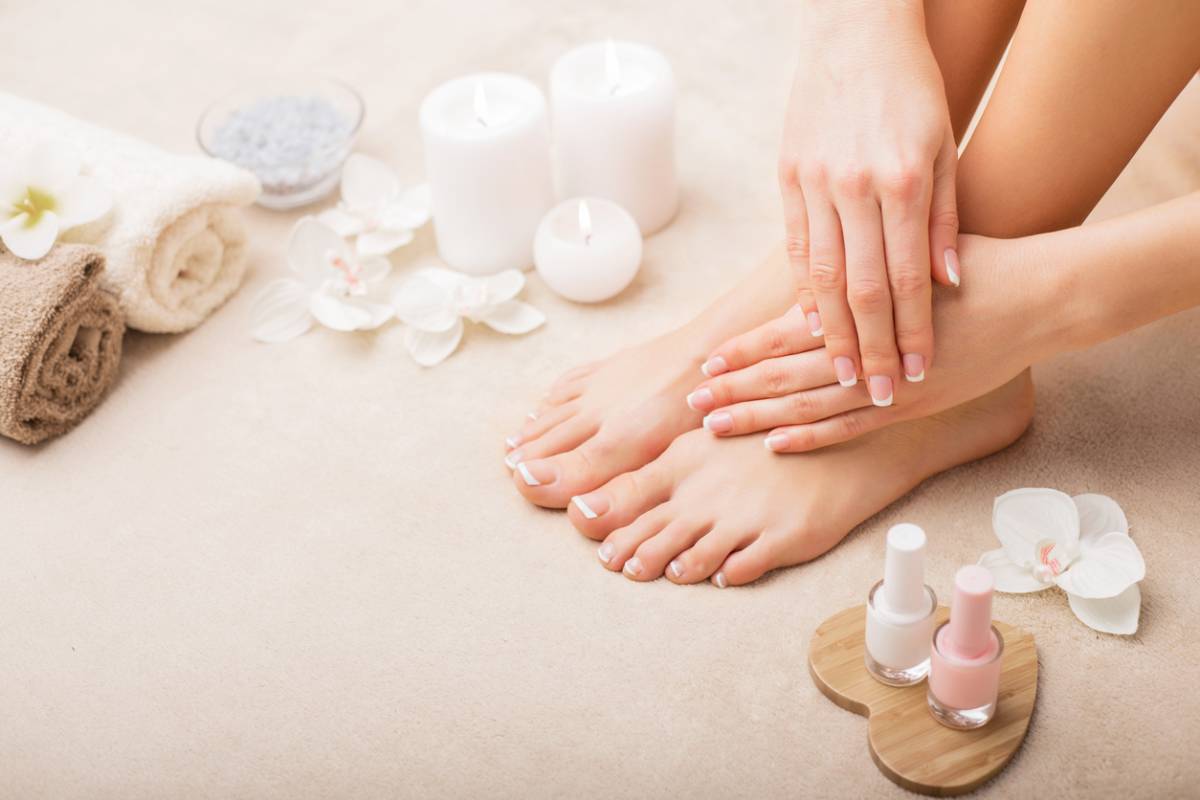 A close-up of a woman's manicured feet surrounded by various spa products, showcasing relaxation and self-care.