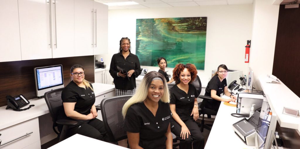 A group of women wearing black shirts seated at a desk, engaged in discussion or collaboration.