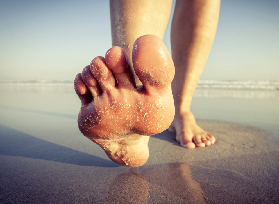 A person strolls along the beach, leaving footprints in the soft sand underfoot.